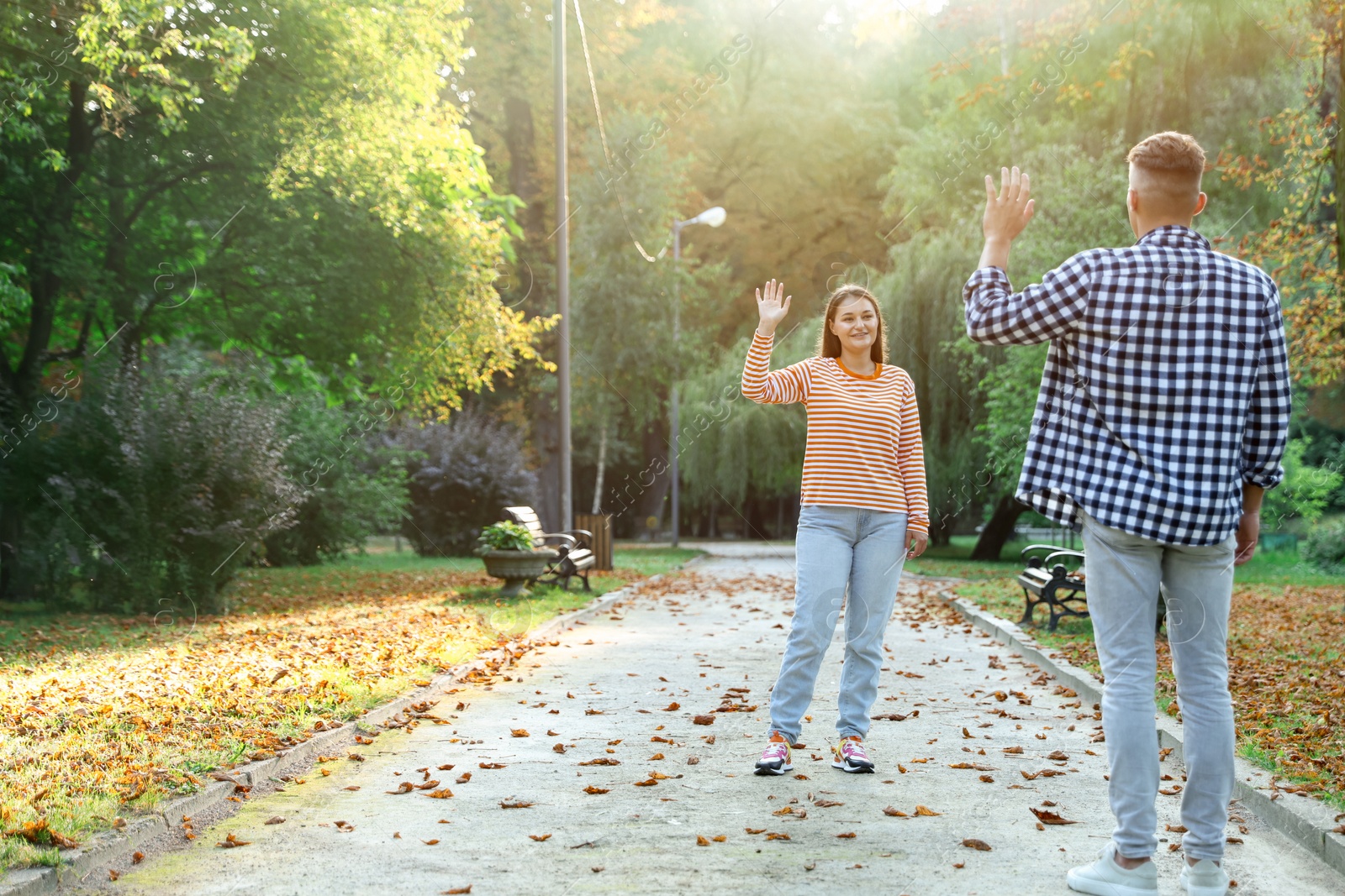 Photo of Man waving goodbye to his friend in park, back view