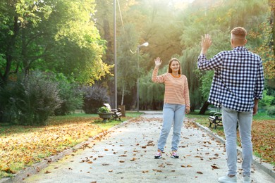 Photo of Man waving goodbye to his friend in park, back view