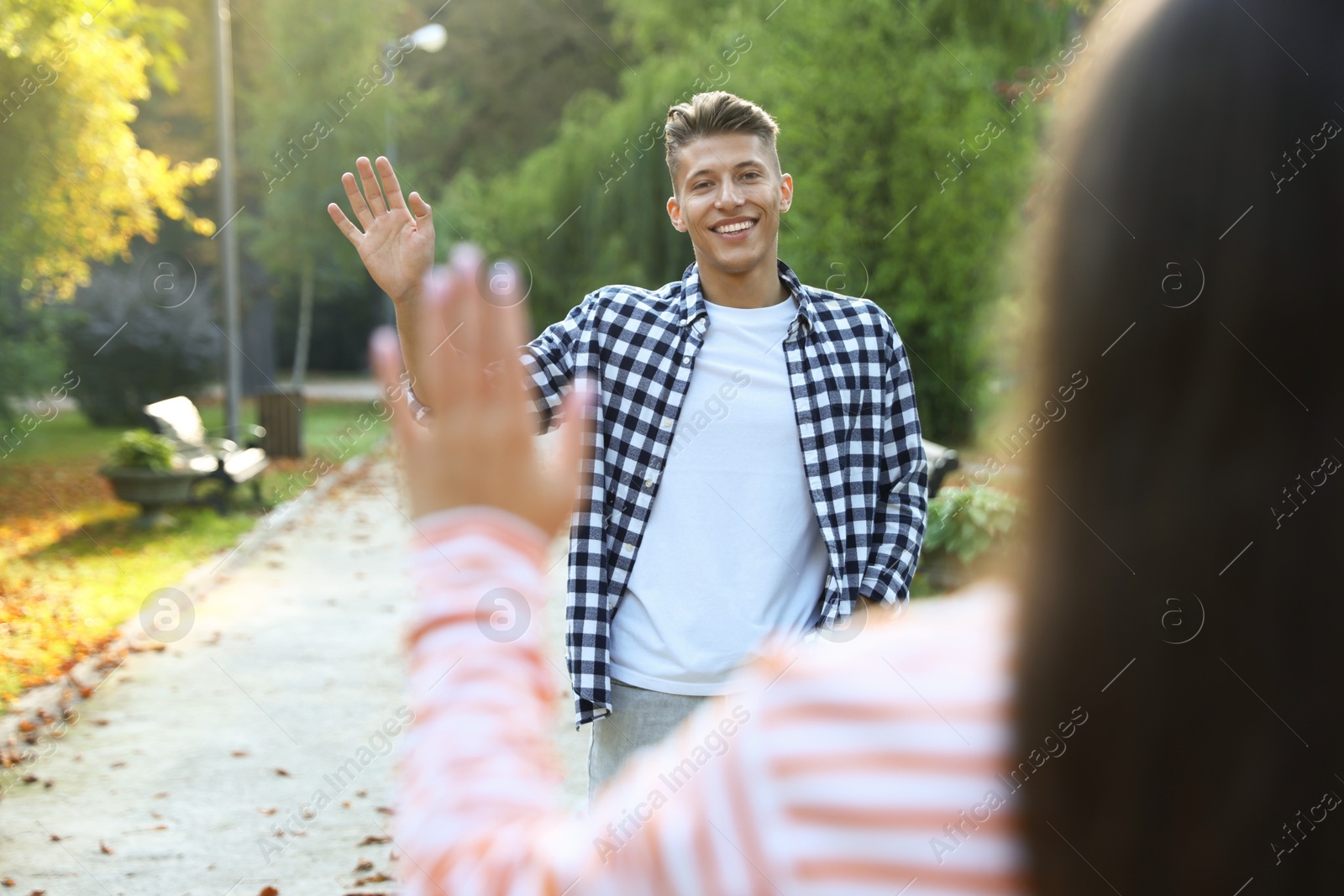 Photo of Man waving goodbye to his friend in park, selective focus