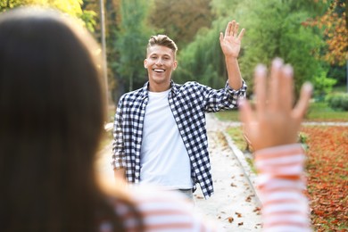 Photo of Woman waving goodbye to her friend in park, selective focus