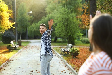 Photo of Woman waving goodbye to her friend in park, selective focus