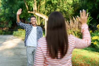 Photo of Woman waving goodbye to her friend in park, selective focus