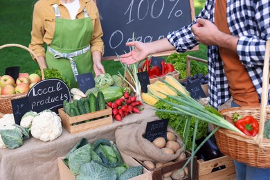 Photo of Man choosing fresh vegetables from stall at farmer's market, closeup