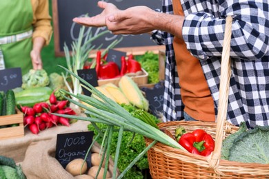 Photo of Man choosing fresh vegetables from stall at farmer's market, closeup