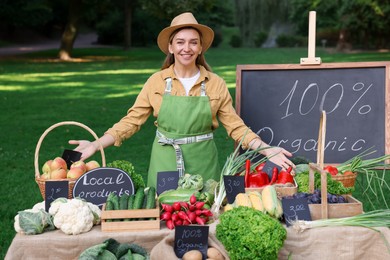 Photo of Happy farmer near stall with different fresh vegetables at market