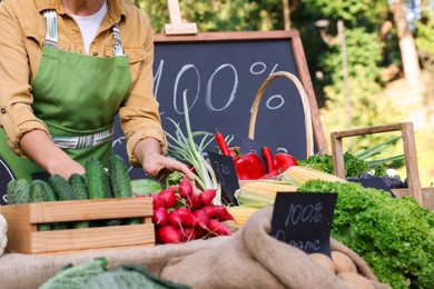Photo of Farmer near stall with different fresh vegetables at market, closeup