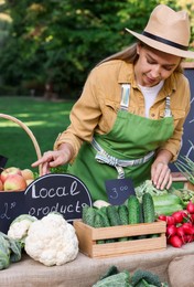 Photo of Happy farmer near stall with different fresh vegetables at market
