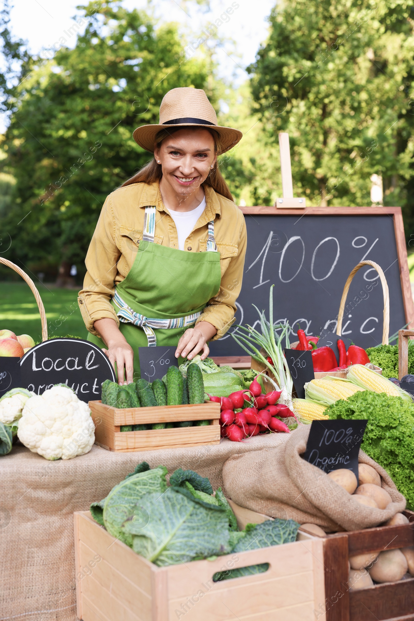 Photo of Happy farmer near stall with different fresh vegetables at market