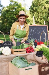 Photo of Happy farmer near stall with different fresh vegetables at market