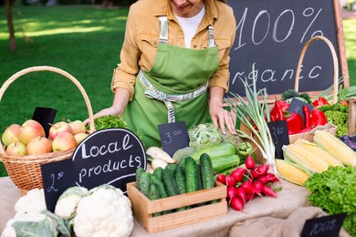 Photo of Farmer near stall with different fresh vegetables at market, closeup