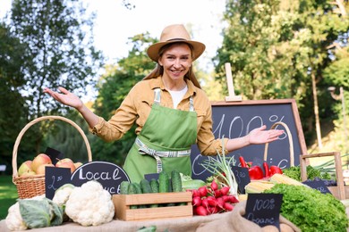 Photo of Happy farmer near stall with different fresh vegetables at market