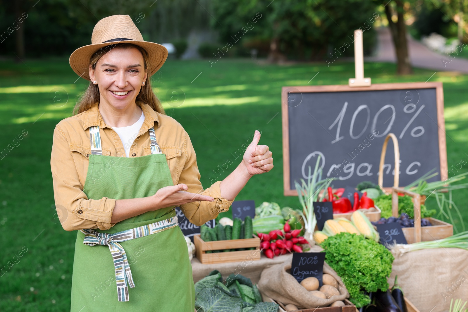 Photo of Happy farmer near stall with different fresh vegetables at market