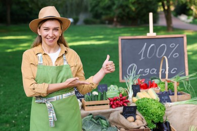Photo of Happy farmer near stall with different fresh vegetables at market