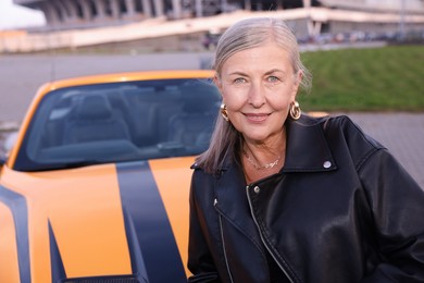 Photo of Stylish senior woman near modern cabriolet outdoors. Space for text