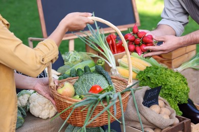 Photo of Woman choosing fresh vegetables from stall at farmer's market, closeup