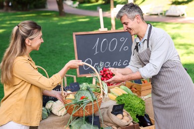 Photo of Woman choosing fresh vegetables from stall at farmer's market