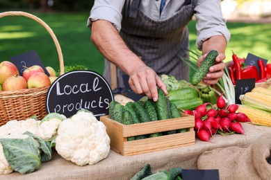 Photo of Farmer near stall with different fresh vegetables at market, closeup