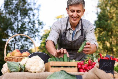 Photo of Farmer near stall with different fresh vegetables at market