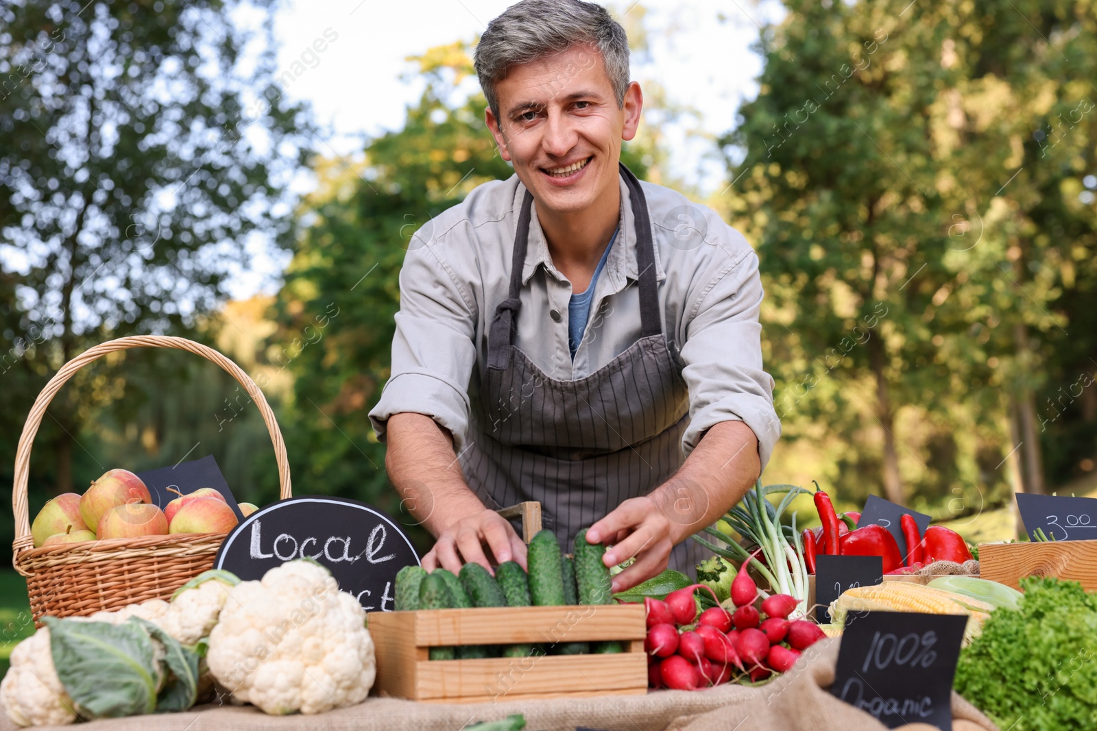 Photo of Farmer near stall with different fresh vegetables at market