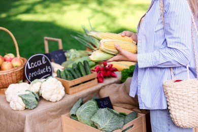 Photo of Woman choosing fresh vegetables from stall at farmer's market, closeup