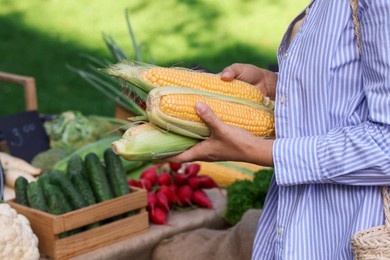 Photo of Woman choosing fresh vegetables from stall at farmer's market, closeup