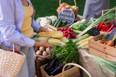 Photo of Woman choosing fresh vegetables from stall at farmer's market, closeup