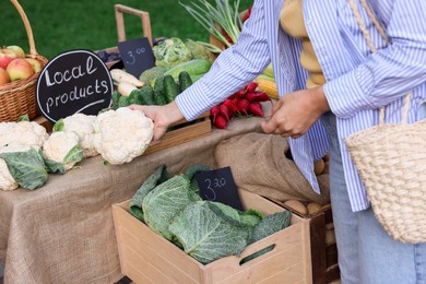 Photo of Woman choosing fresh vegetables from stall at farmer's market, closeup