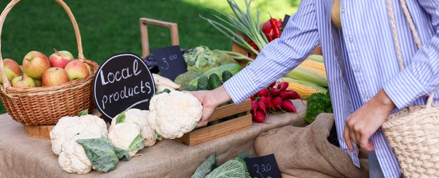 Photo of Woman choosing fresh vegetables from stall at farmer's market, closeup