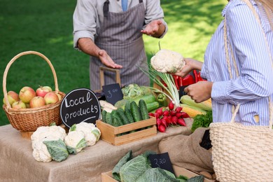 Photo of Woman choosing fresh vegetables from stall at farmer's market, closeup