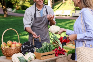 Photo of Woman choosing fresh vegetables from stall at farmer's market, closeup