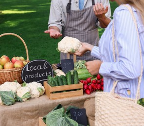Photo of Woman choosing fresh vegetables from stall at farmer's market, closeup