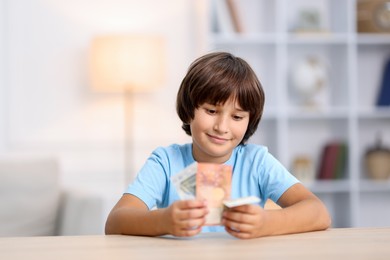 Photo of Boy with pocket money at wooden table indoors