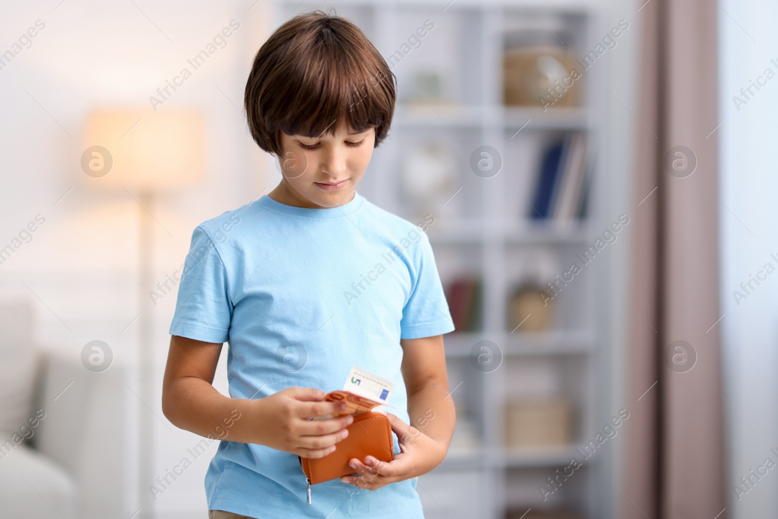 Photo of Boy putting his pocket money into wallet at home