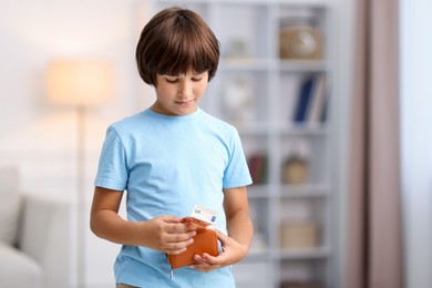 Photo of Boy putting his pocket money into wallet at home