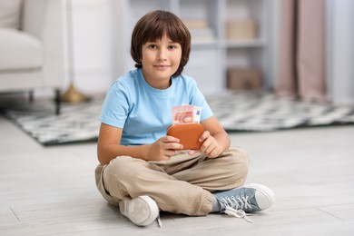 Photo of Boy with pocket money on floor at home
