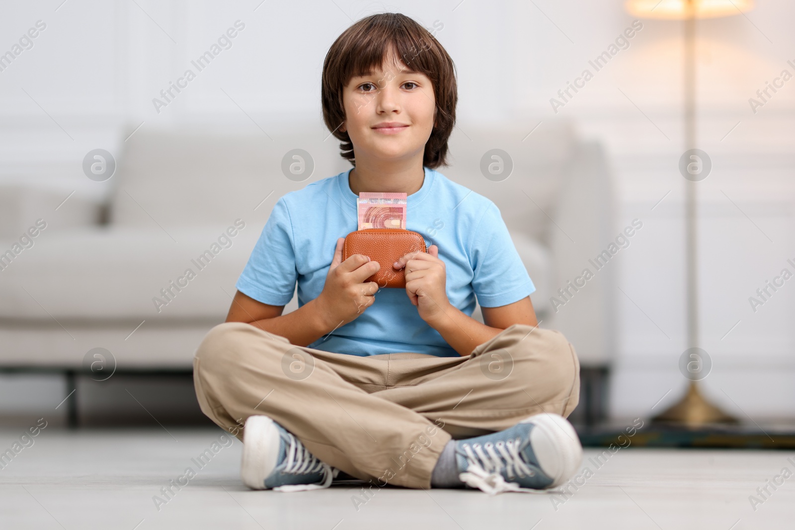 Photo of Boy with pocket money on floor at home