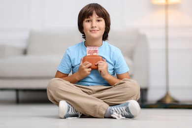 Photo of Boy with pocket money on floor at home