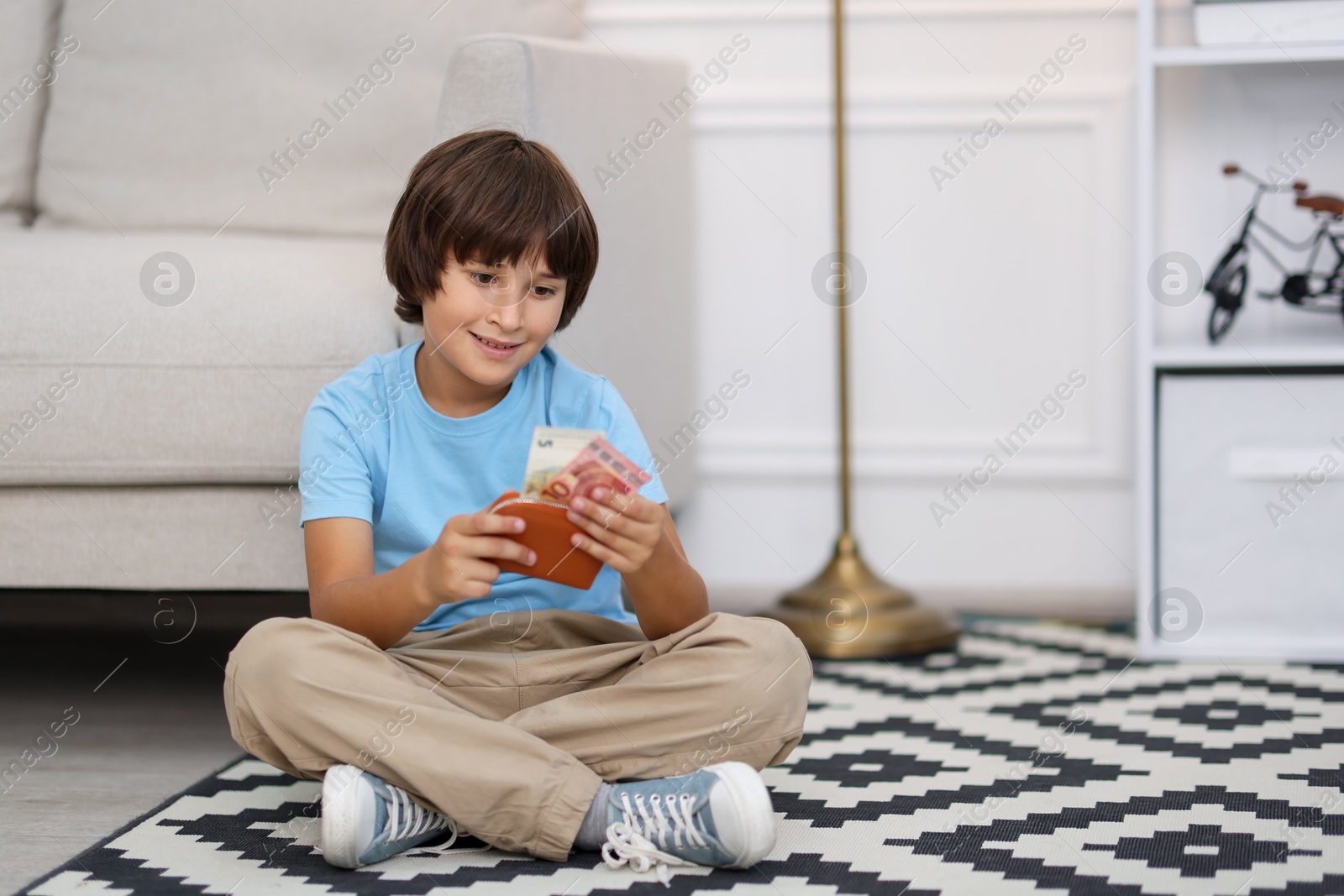 Photo of Boy with pocket money on floor at home. Space for text