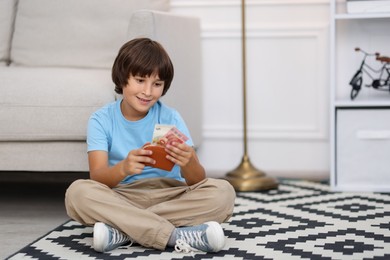 Photo of Boy with pocket money on floor at home. Space for text