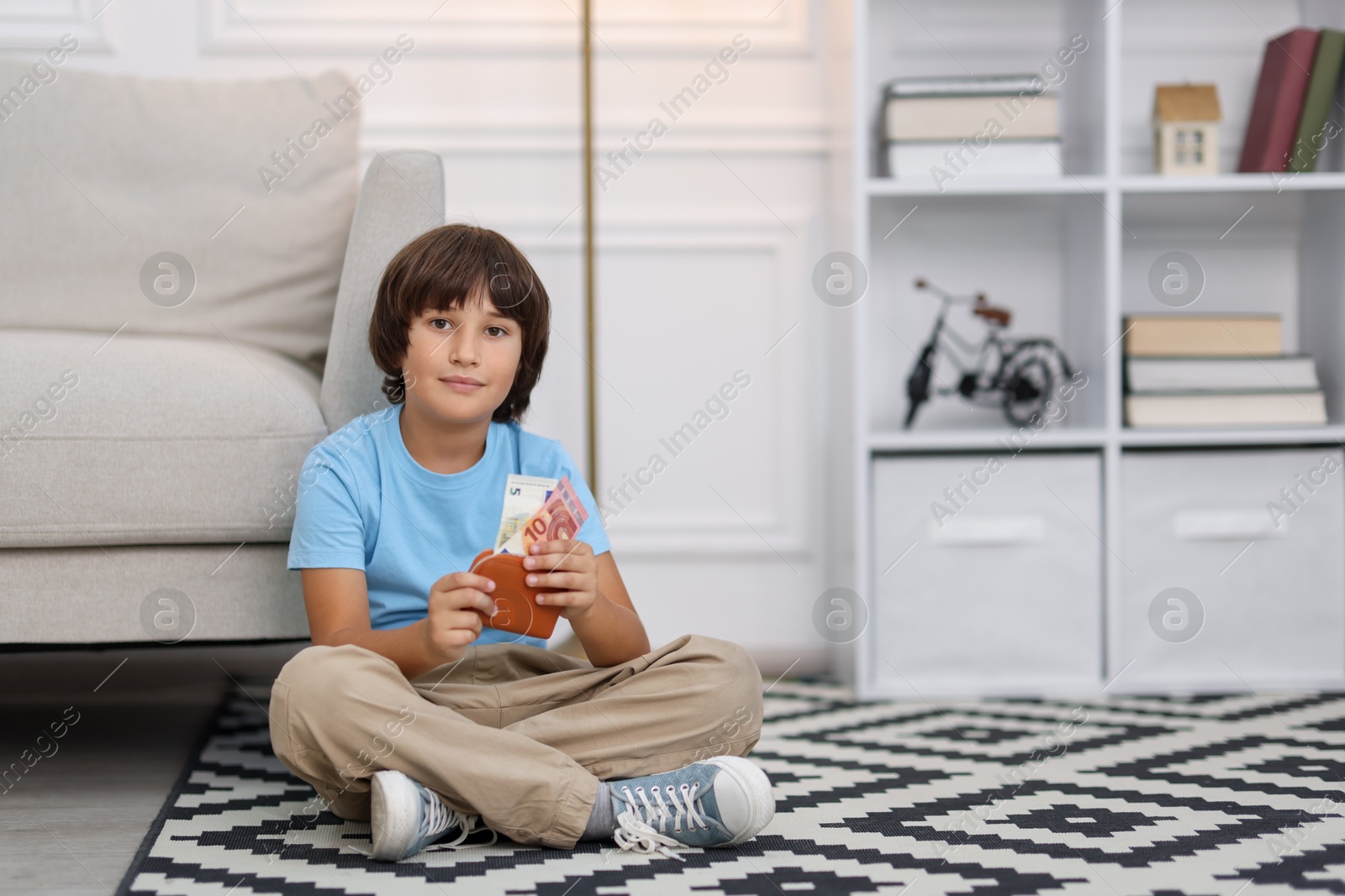Photo of Boy with pocket money on floor at home. Space for text