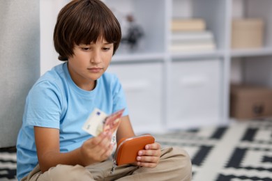Photo of Boy with pocket money on floor at home. Space for text