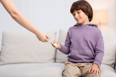 Photo of Mother giving her son pocket money at home, closeup