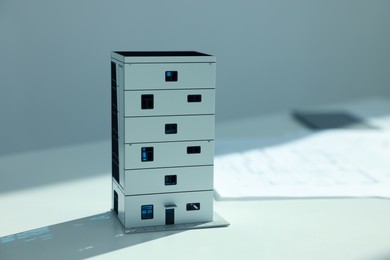 Photo of Real estate. Apartment building model and paperwork on table, closeup