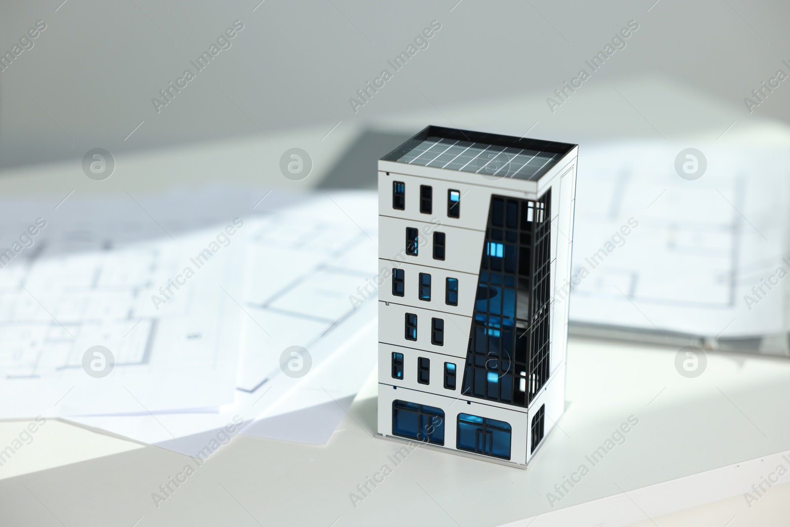 Photo of Real estate. Apartment building model and architectural drawings on white table, closeup