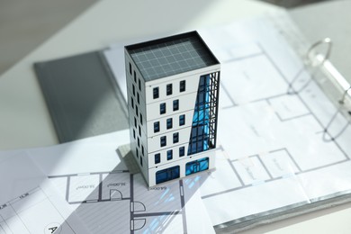 Photo of Real estate. Apartment building model and architectural drawings on table, closeup