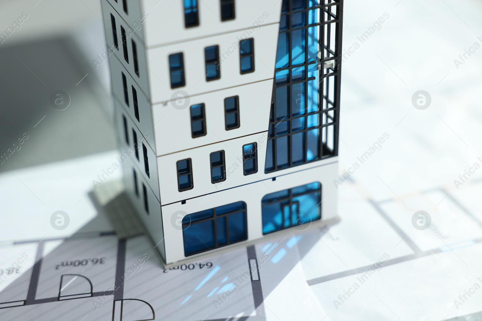 Photo of Real estate. Apartment building model and architectural drawings on table, closeup