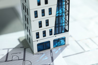 Photo of Real estate. Apartment building model and architectural drawings on table, closeup