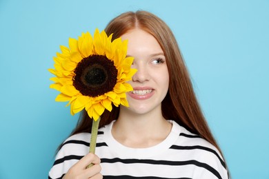 Photo of Teenage girl with sunflower on light blue background
