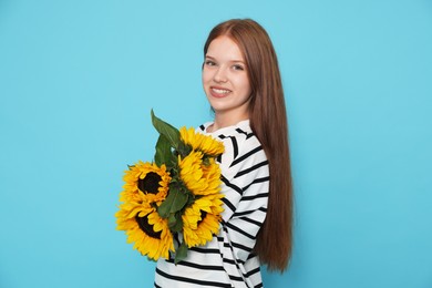 Photo of Teenage girl with bouquet of beautiful sunflowers on light blue background