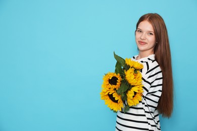 Photo of Teenage girl with bouquet of beautiful sunflowers on light blue background, space for text
